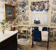 Bathroom with blue toile wallpaper, towel rack and decorative plates