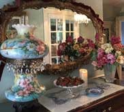 Antique dresser with ornate mirror, painted lamp, flowers and strawberries
