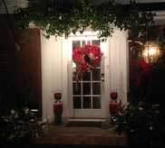 Front door at night with holiday wreath and glowing lanterns