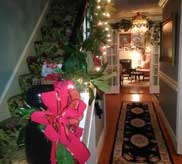 Staircase entryway decorated with Christmas poinsettias and twinkling lights